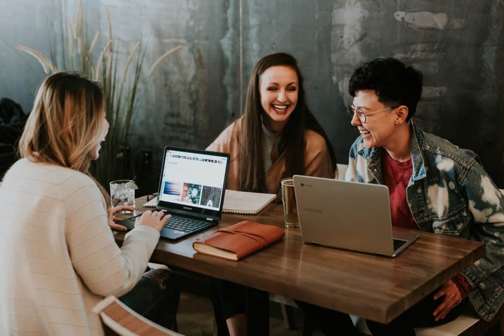 a group of women sitting at a table with laptops