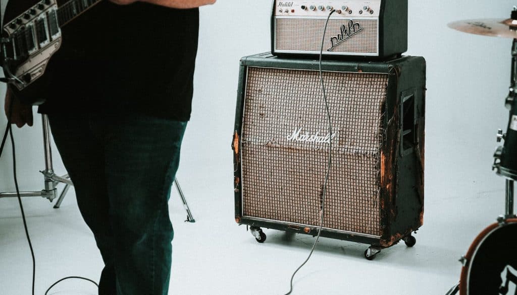 a man standing next to a stack of amps