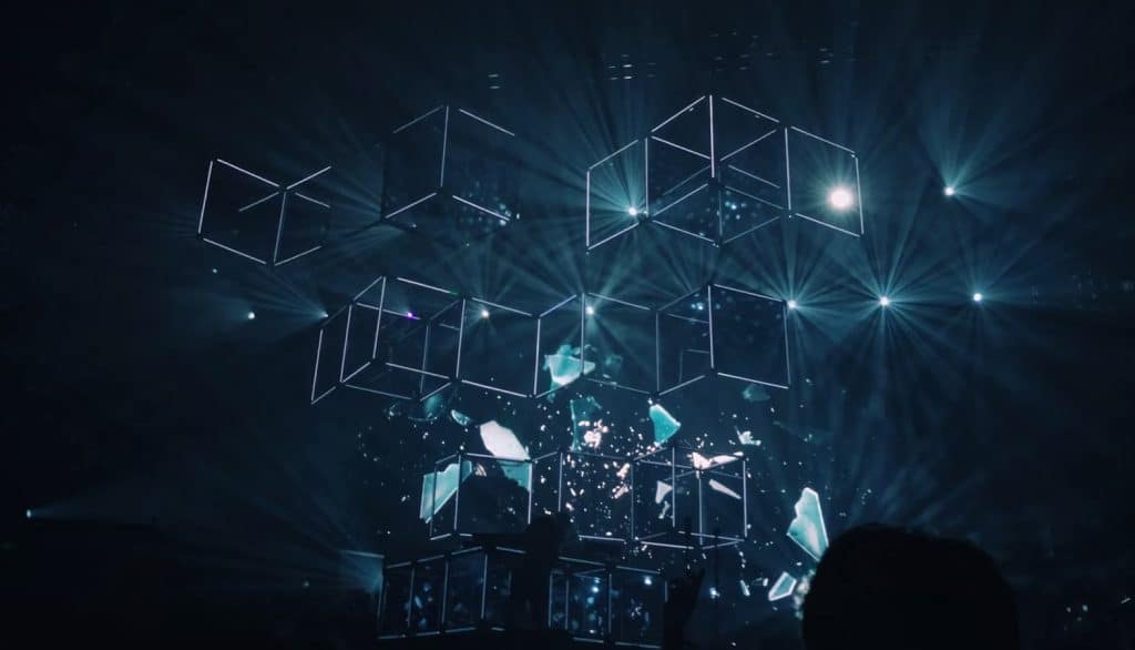 a group of people standing in front of a stage with lights